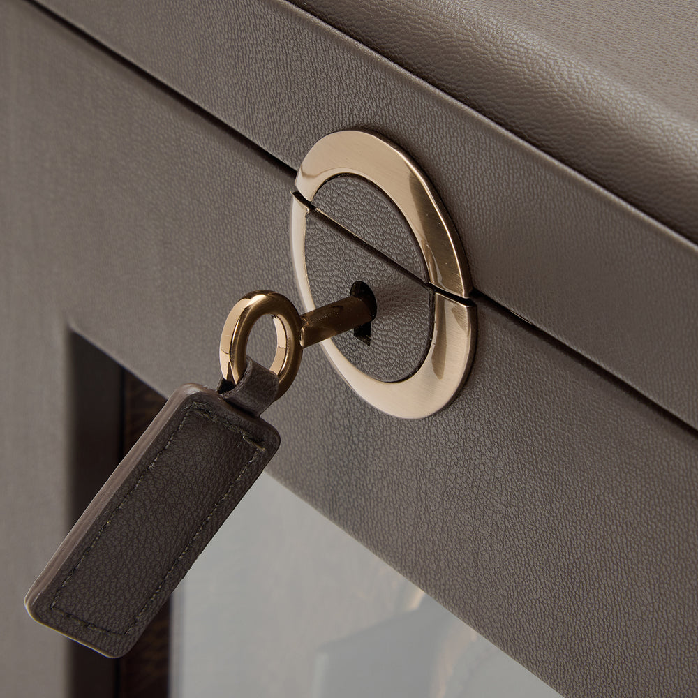 Close-up of a gold keyhole with a key and black tag on a gray surface.