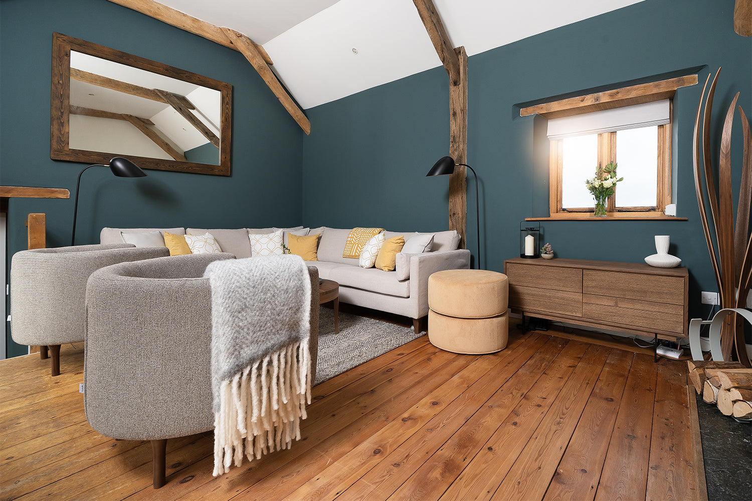 Modern rustic living room with vaulted ceiling, teal accent wall, neutral corner sofa, and oak flooring – styled by Iroka Interiors in Port Isaac.