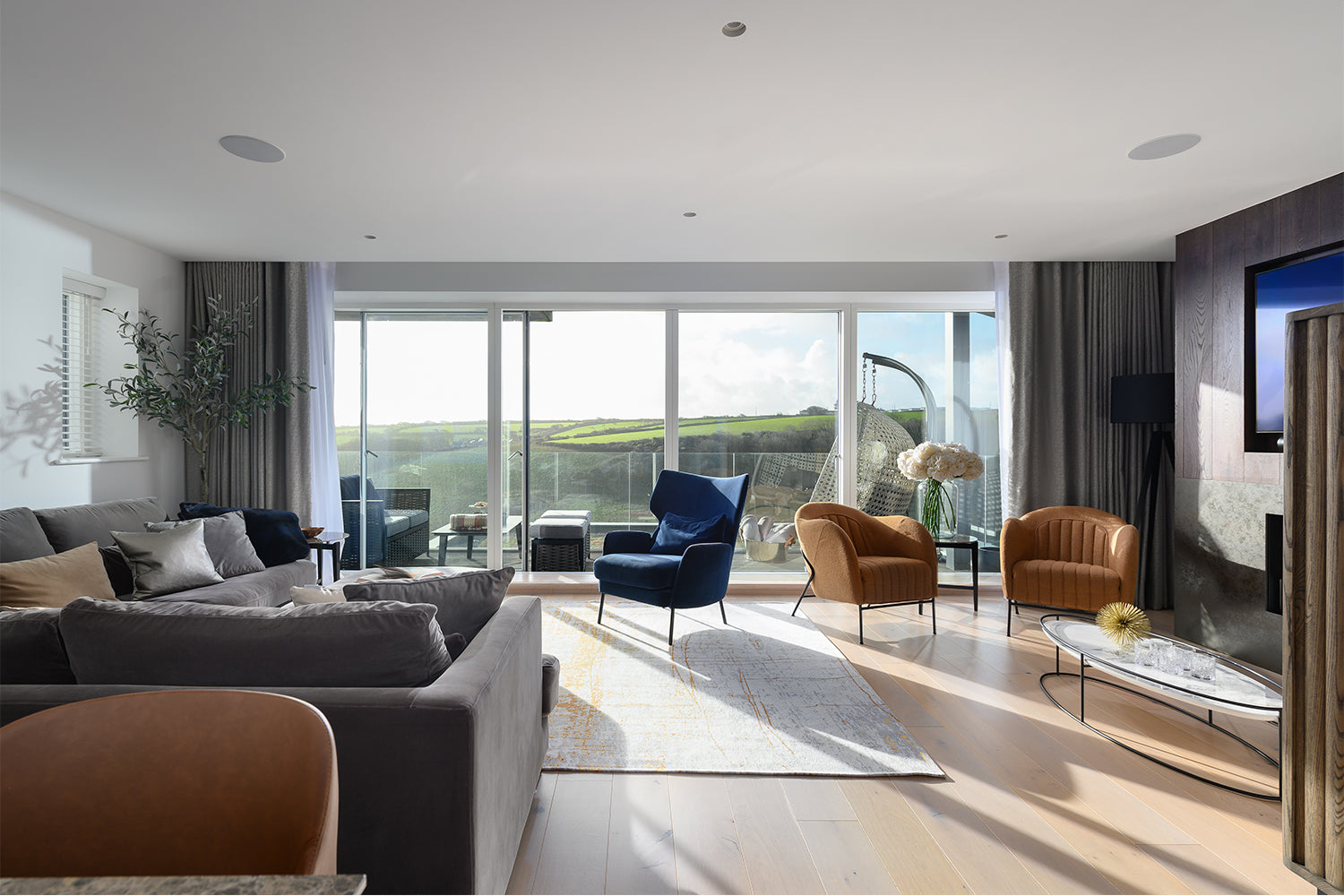 Open-plan luxury living room at Paradise View with floor-to-ceiling glass doors, velvet seating, oak flooring, and curated modern artwork - interior design by Iroka