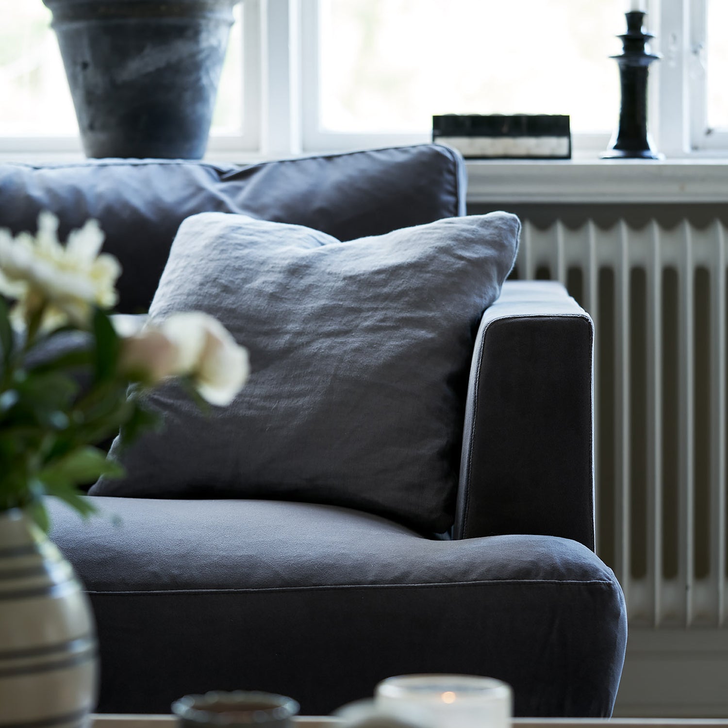 Close-up of a charcoal grey sofa armrest and cushion, showcasing Mastrella’s tailored upholstery and plush comfort - styled with soft natural light and minimal accessories.