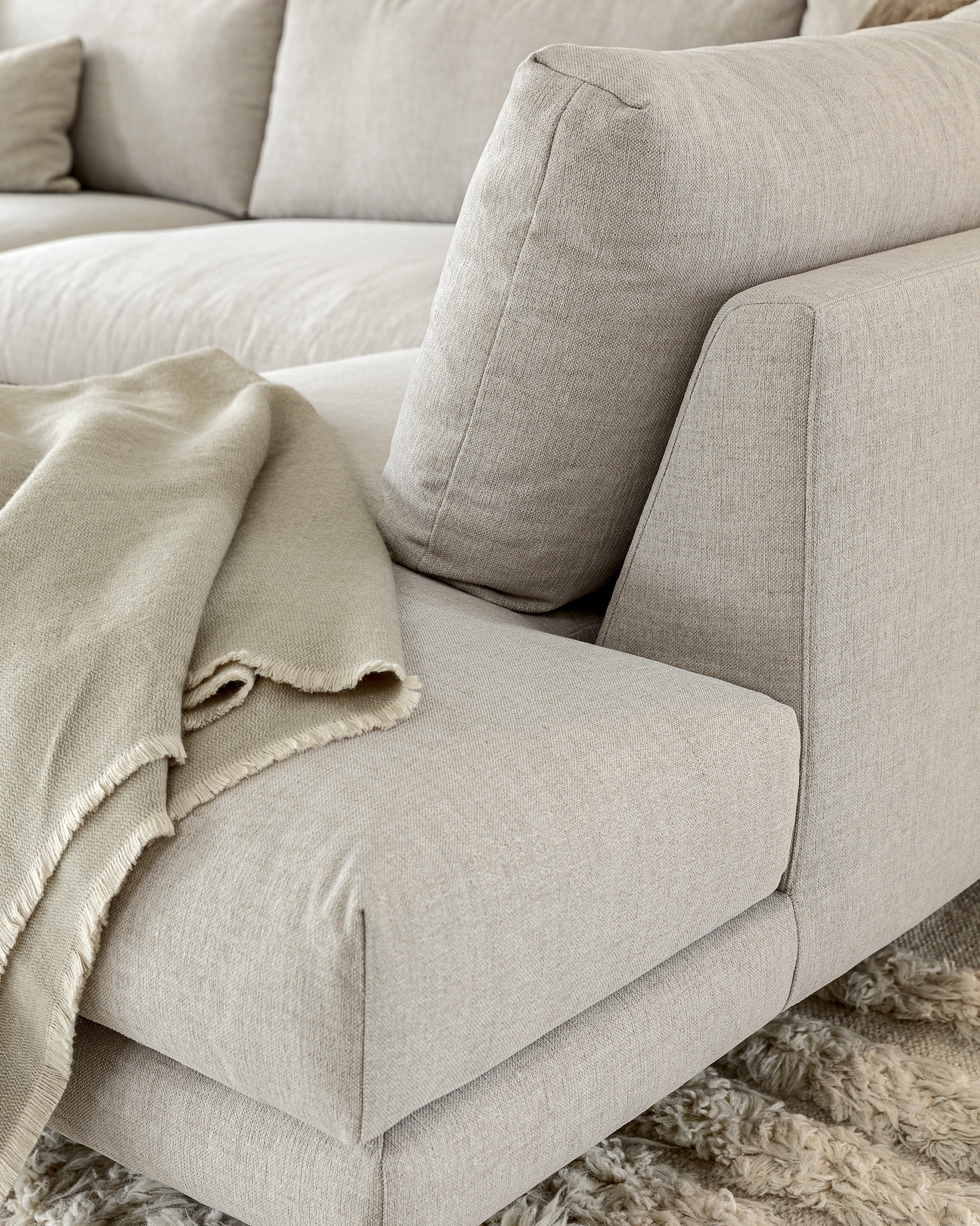 Light gray sofa with a blanket on a textured rug