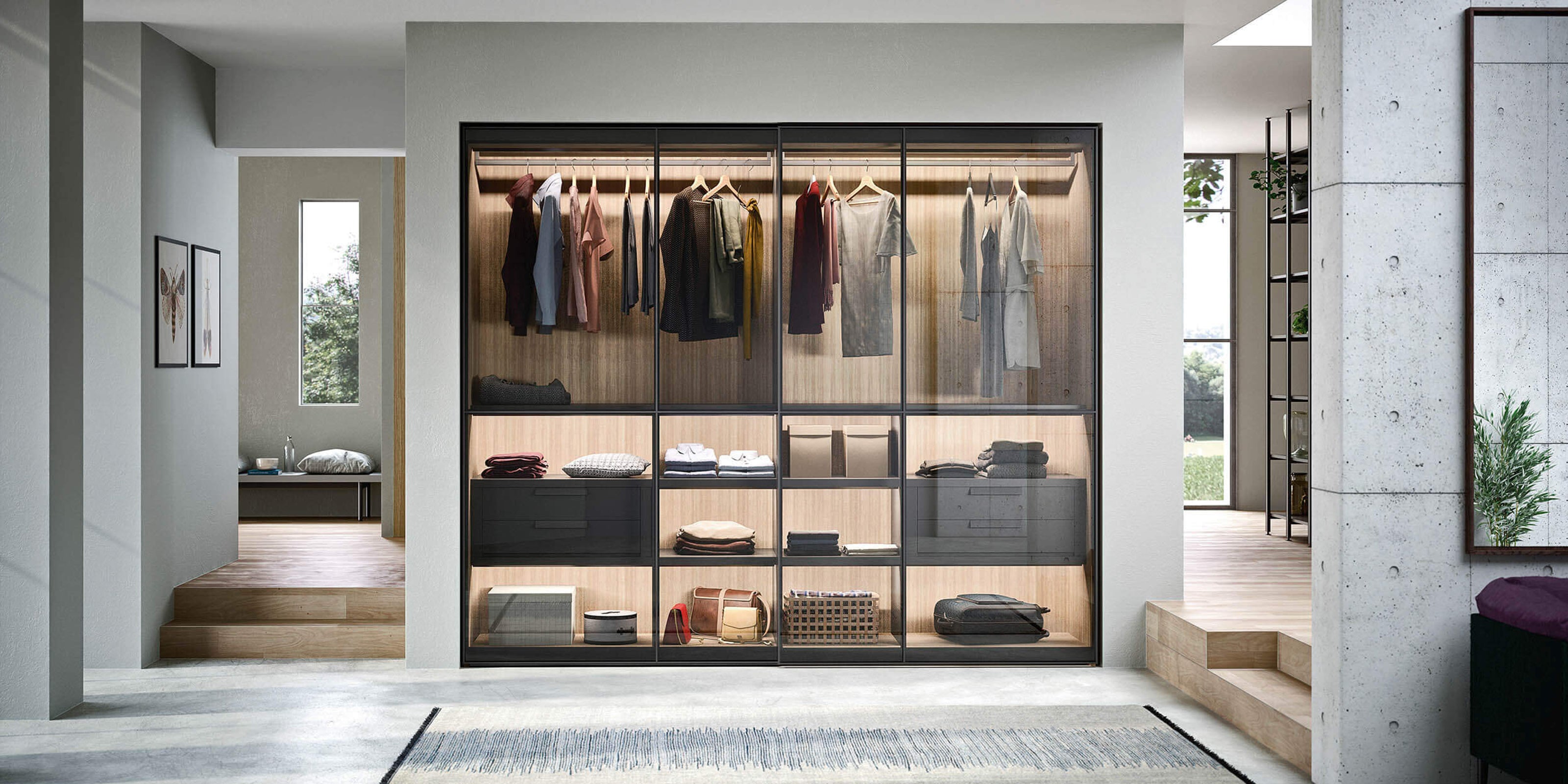 Bespoke fitted wardrobe with glass sliding doors, integrated lighting, and custom shelving – Interiors for luxury modern homes in Cornwall, combining elegant storage solutions with tailored furniture craftsmanship.