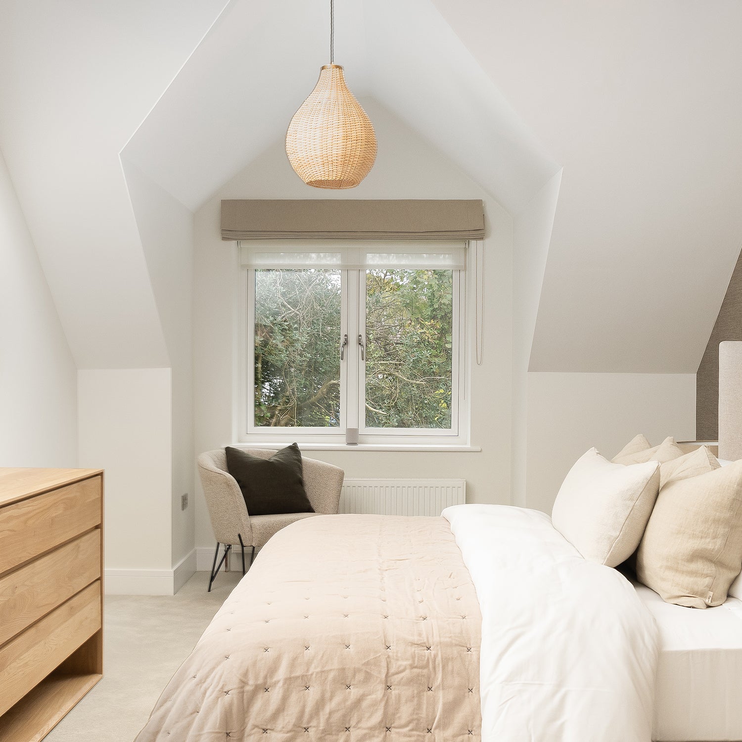 Scandi-inspired attic bedroom featuring a bespoke roman blind layered over a sheer roller, styled in soft neutrals for a warm and minimal look by Iroka.
