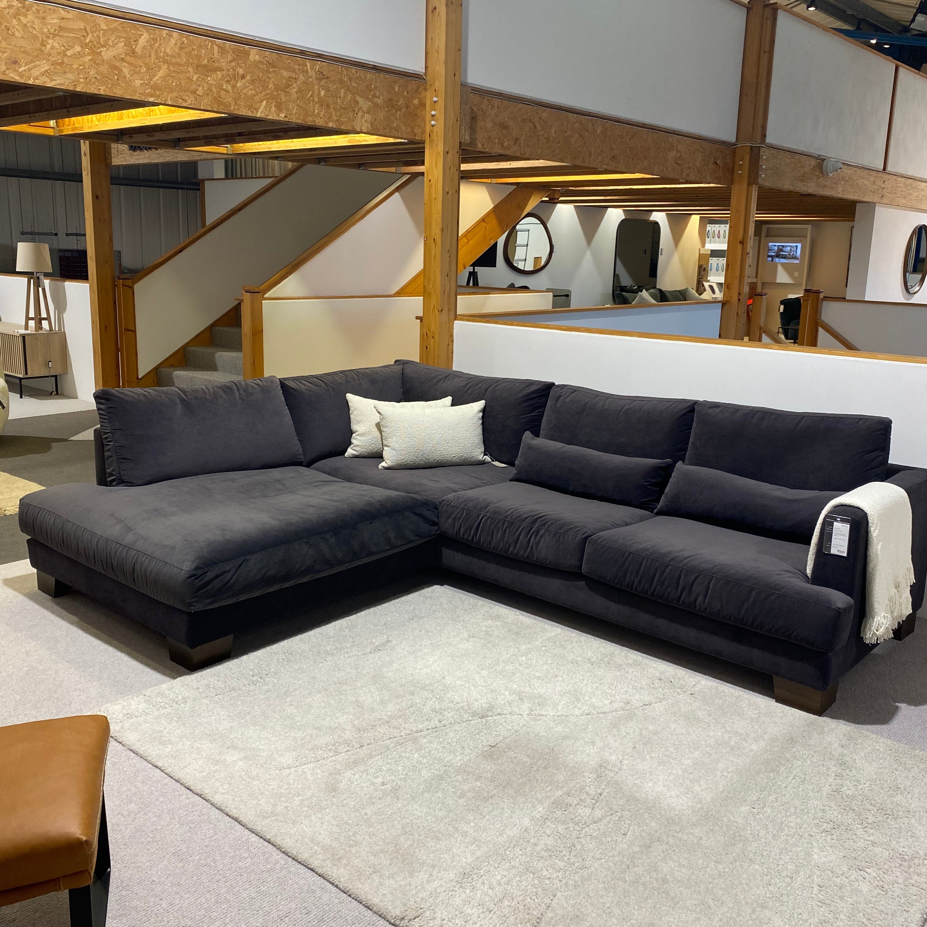 Gray sofa with white cushions on a gray floor in a store setting