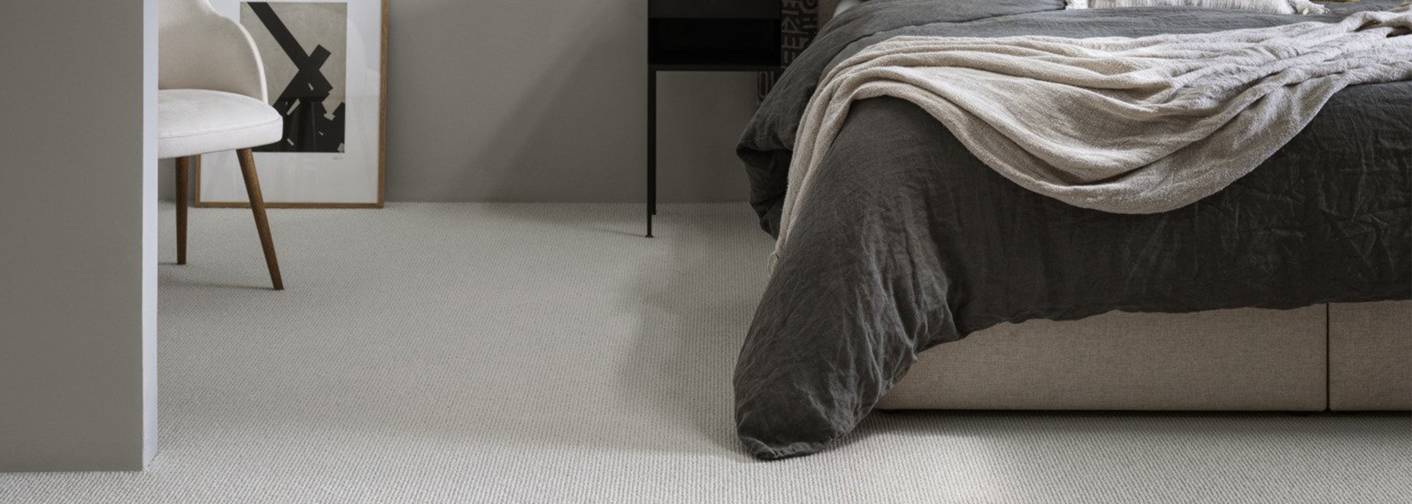 Modern bedroom featuring a soft, light grey carpet flooring with a plush texture, complemented by a neutral-toned bed and minimalist décor.