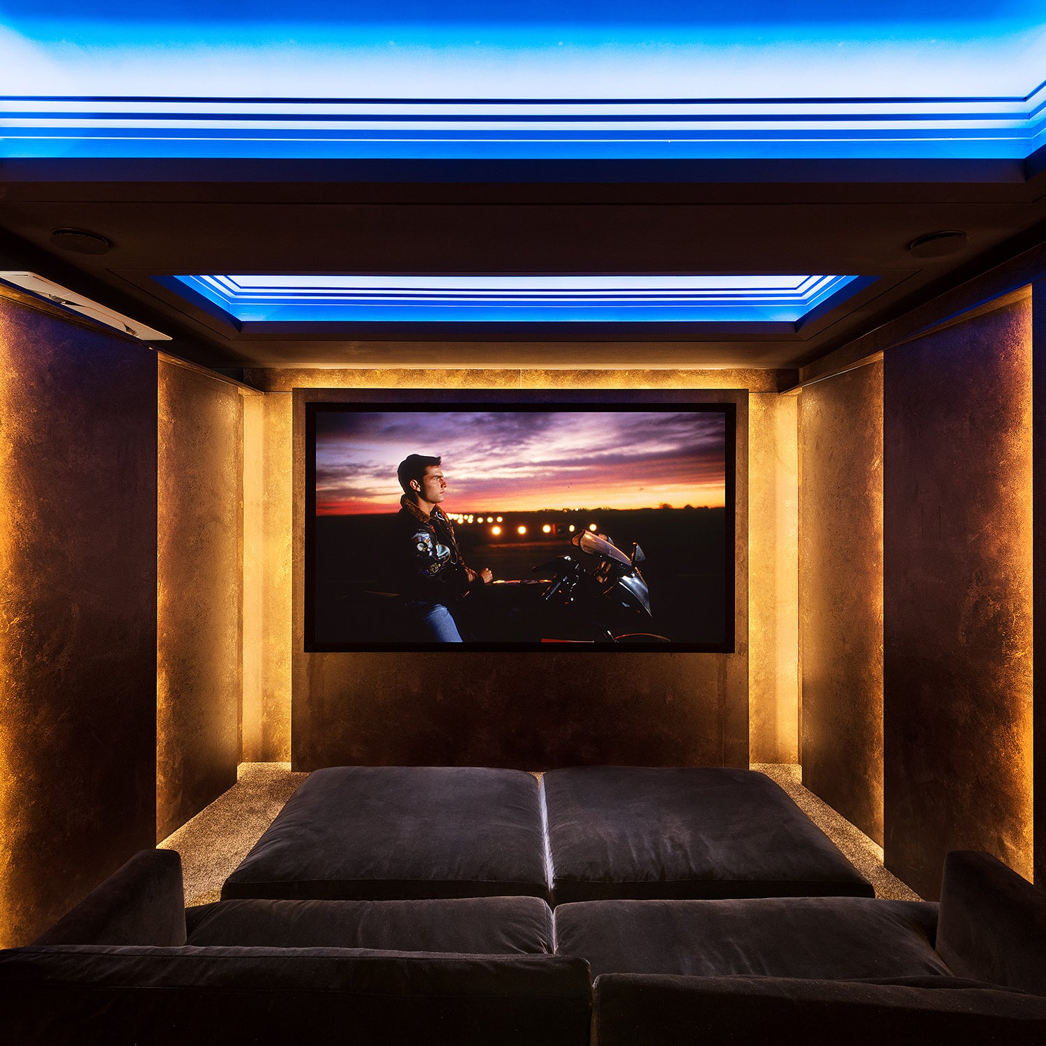 Bespoke home cinema room with ambient LED ceiling lighting, velvet seating, and gold-accented acoustic wall panels – custom entertainment space by Iroka Interiors Cornwall.