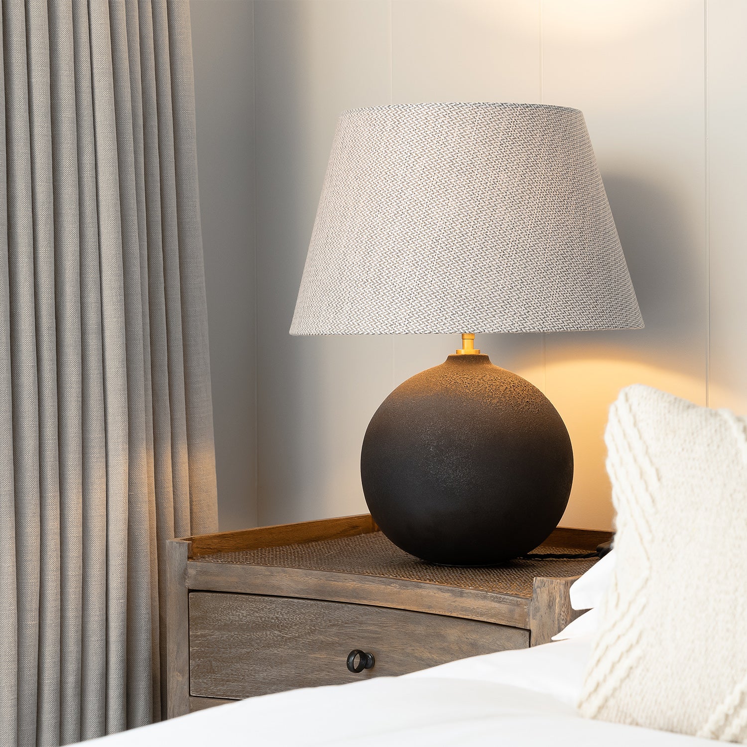 Elegant wave-fold curtains in a neutral linen fabric paired with a rustic wooden bedside table and modern ceramic lamp — bespoke window dressing