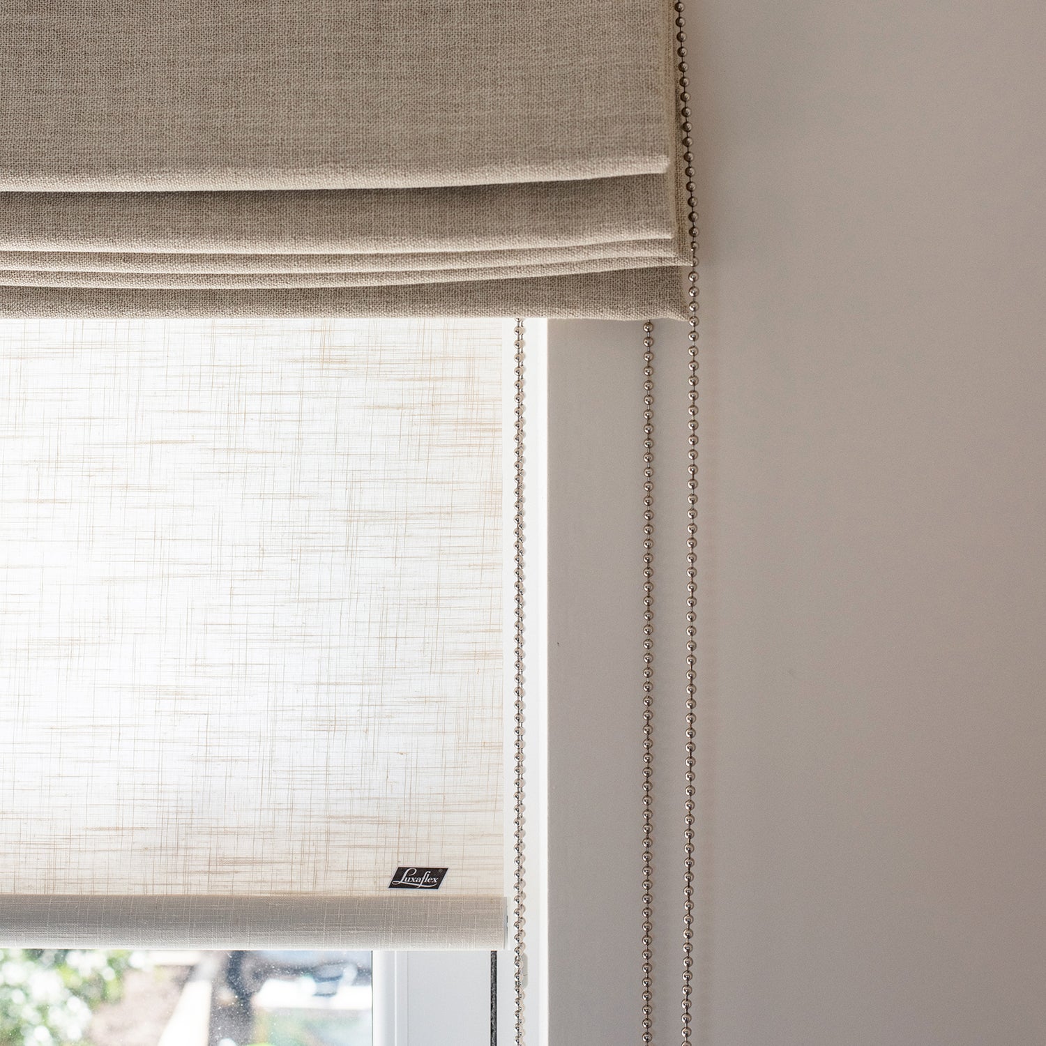 Close-up of layered neutral linen Roman blind with subtle textured sheer privacy shade, featuring ball chain mechanism – bespoke window blinds.
