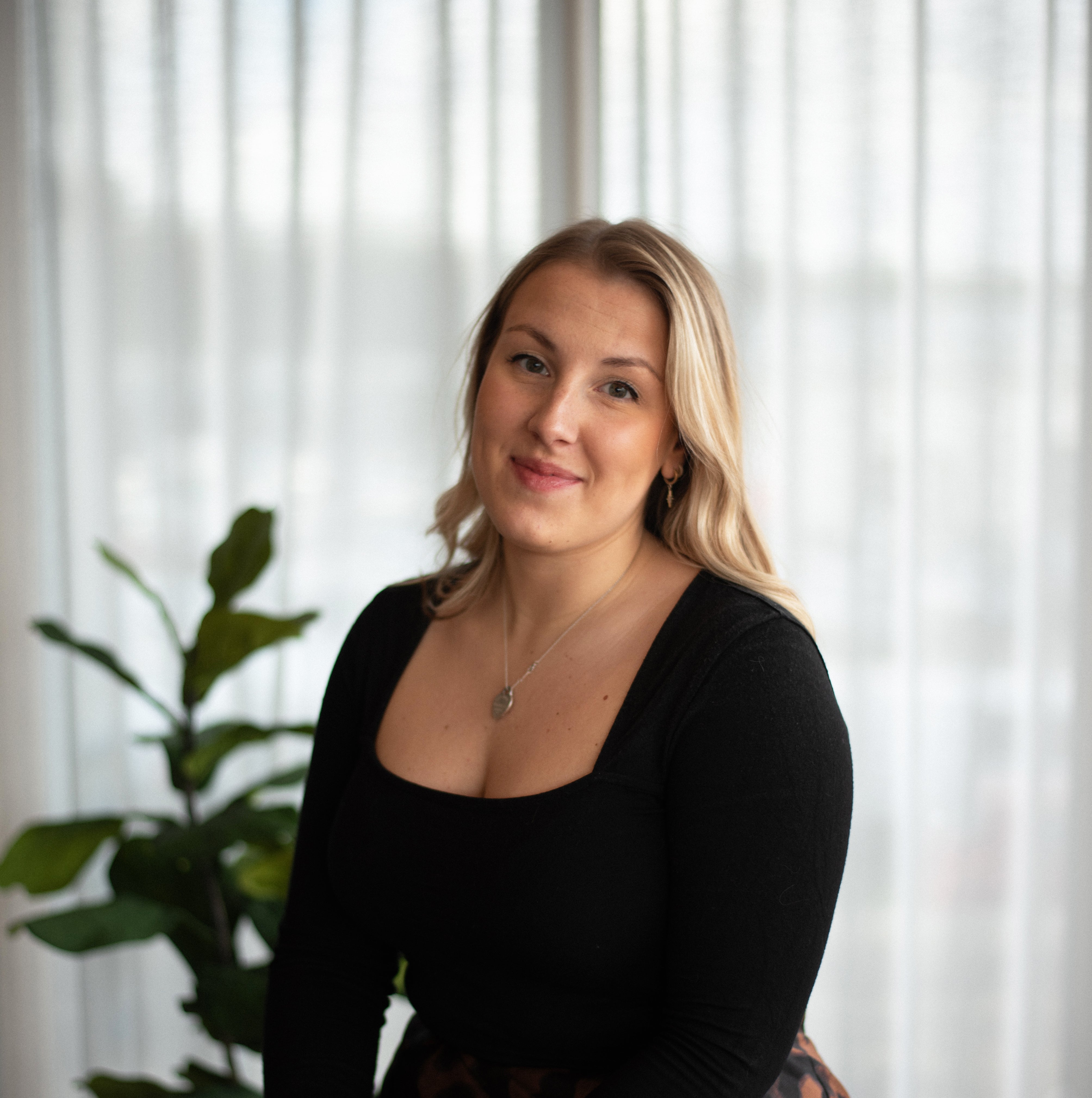 Dani, lead interior designer at Iroka Interiors in Cornwall, pictured in a modern showroom with soft natural light and contemporary styling – expert in bespoke home design and furniture solutions.