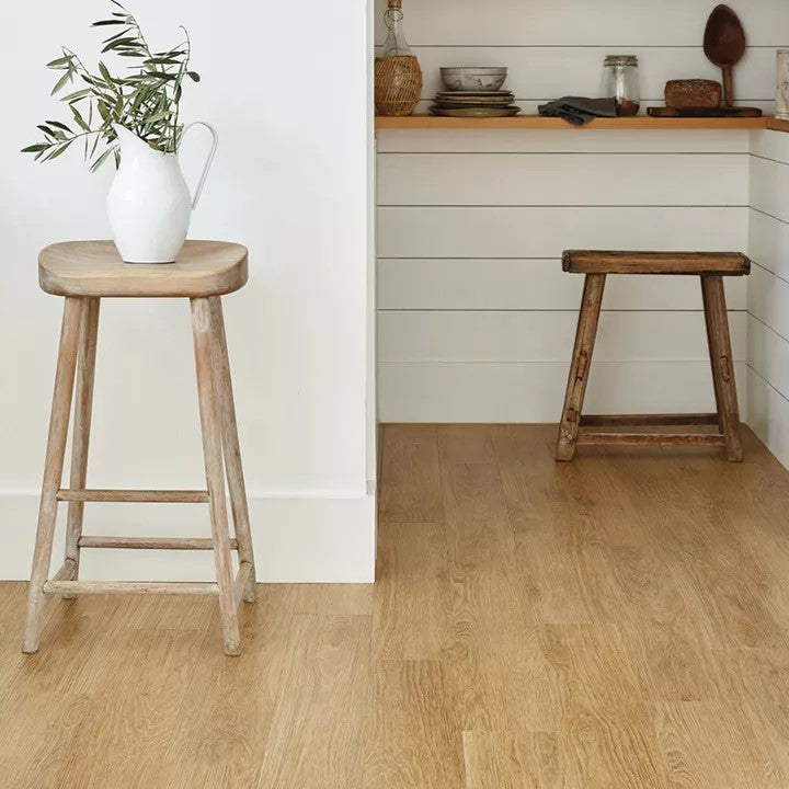 Rustic kitchen nook with Form Amber Oak luxury vinyl tile flooring, featuring a natural wood grain finish, white shiplap walls, and reclaimed wooden stools for a warm, country-inspired interior.