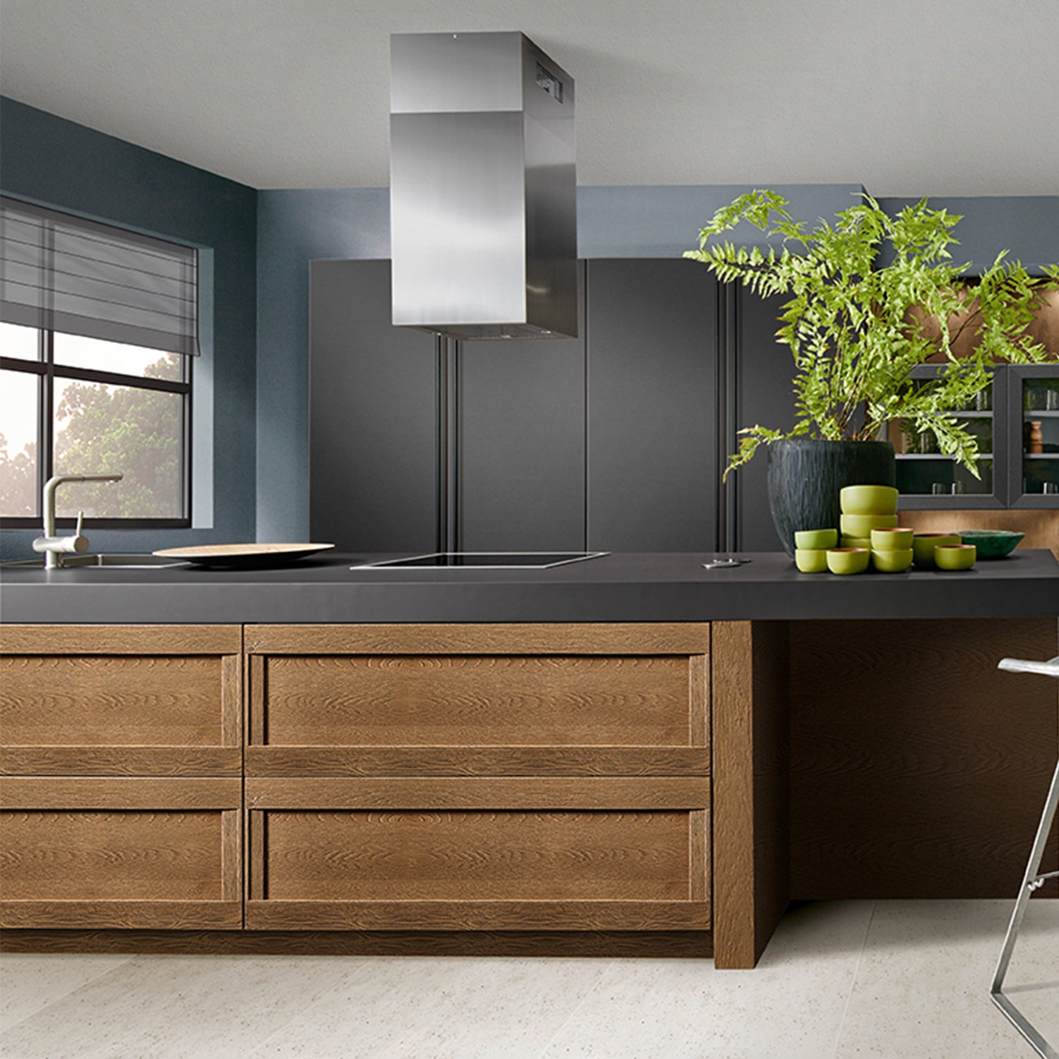 Bespoke in-frame Schröder German kitchen with rich oak cabinetry, matte black island worktop, integrated induction hob, and contemporary extractor hood – modern kitchen design by Iroka Interiors in Cornwall.