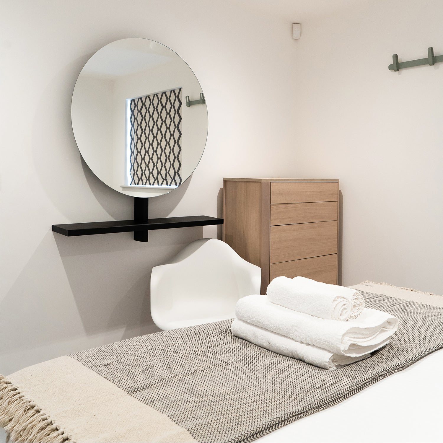 Elegant hotel bedroom designed by Iroka Interiors featuring a calming neutral palette, round statement mirror, natural textures, and contemporary furnishings – luxury interior design in Cornwall.