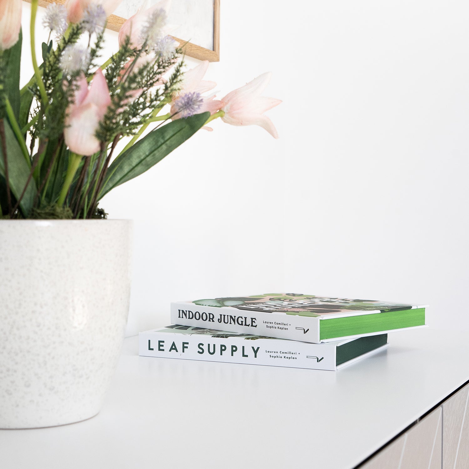 "Bright and modern hotel interior with white minimalist side table, floral arrangement in ceramic vase, and stylish coffee table books – curated by Iroka Interiors for luxury hospitality design in Cornwall.