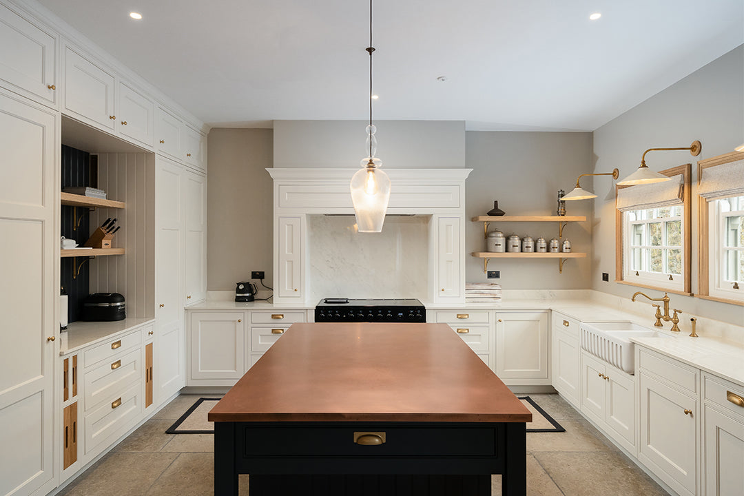 Luxury bespoke kitchen with natural stone walls, timber open shelving, and central island with copper worktop – custom kitchen design and installation by Iroka Interiors in Cornwall.