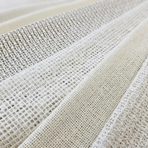 Close-up of Camengo Pesie sheer fabrics in soft neutral tones, showcasing open weave textures ideal for light-filtering curtains, available at Iroka Interiors in Cornwall.
