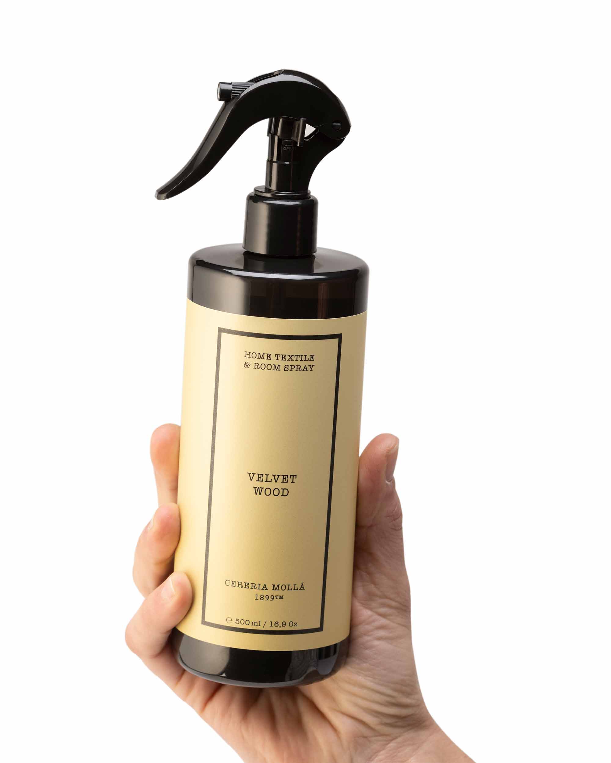 Hand holding a bottle of 'Velvet Wood' room spray with a beige label.