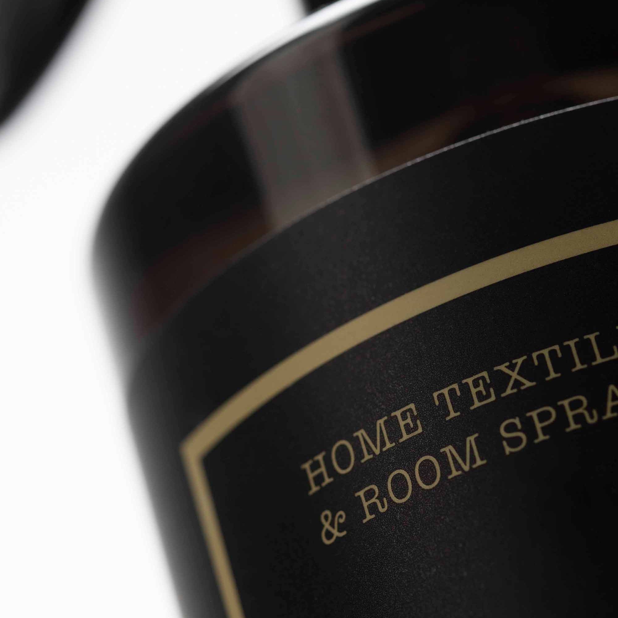 Close-up of a bottle with a label reading 'Home Textile & Room Spray' on a white background.