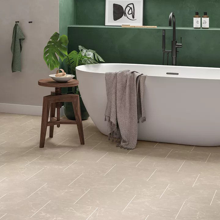 Modern bathroom with Signature Tortira Classic Marble luxury vinyl tile flooring, featuring a soft beige marble effect, freestanding white bathtub, dark green accent wall, and minimalist natural wood accessories.