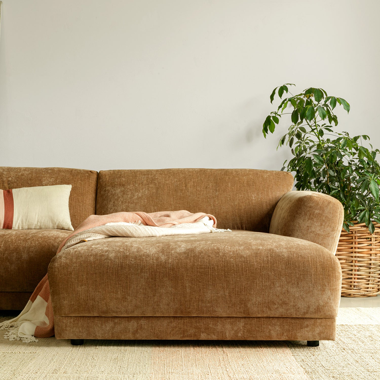 Vintage-inspired velvet chaise sofa in a warm caramel tone with minimalist backrest, styled with a neutral throw and indoor plant in a bright, modern living space.