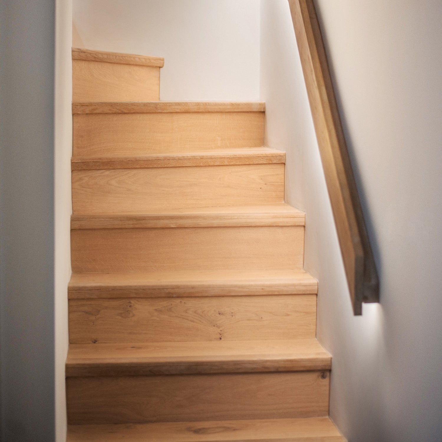 Modern oak staircase with integrated LED wall lighting and minimalist black handrail at Pentire Townhouse, Newquay.