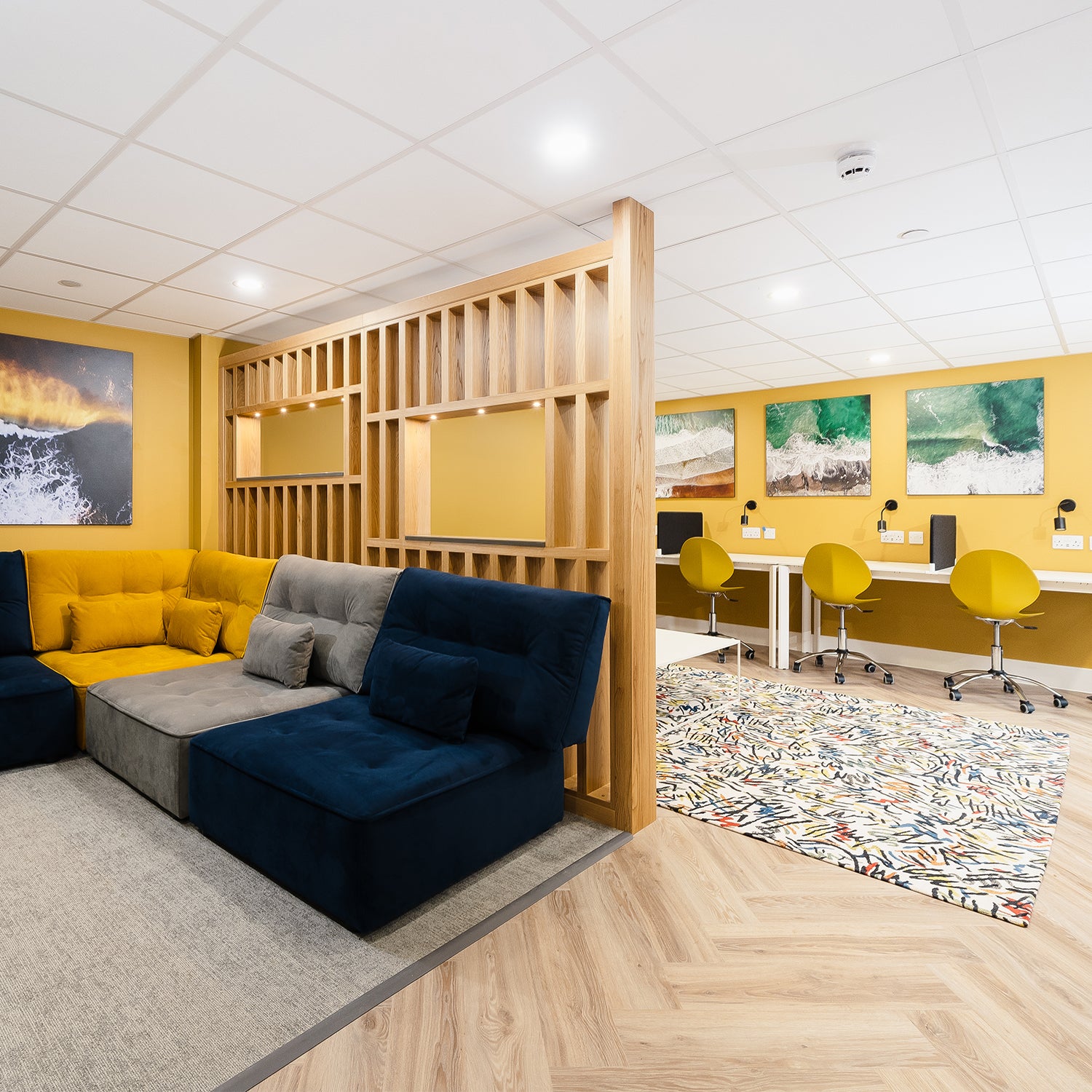 Modern student accommodation in Falmouth designed by Iroka Interiors, featuring a vibrant co-living space with modular sofas, dedicated study desks, bold yellow accents, and contemporary coastal artwork for a stylish and functional student lifestyle.