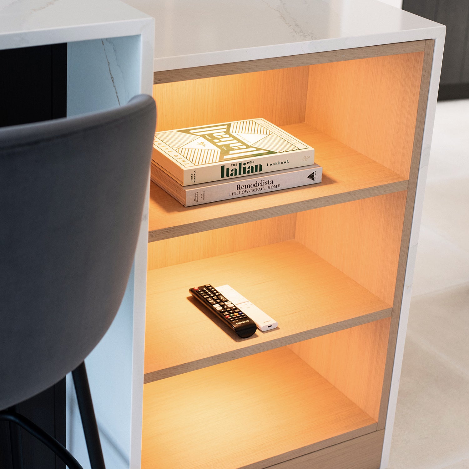 Modern illuminated kitchen island shelf with oak wood finish, integrated LED lighting, and neatly styled cookbooks – bespoke kitchen design feature by Iroka Interiors, Cornwall.