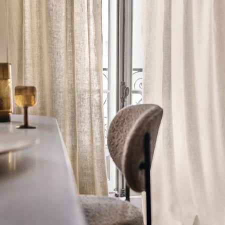 Soft neutral linen curtains gently framing a classic French window.