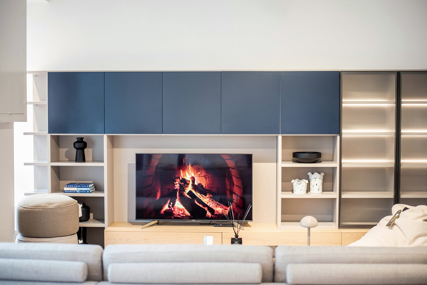 Novamobili wall unit display. Cozy fireplace shown on TV. Styled and dressed with blue layered books and detailed vases.