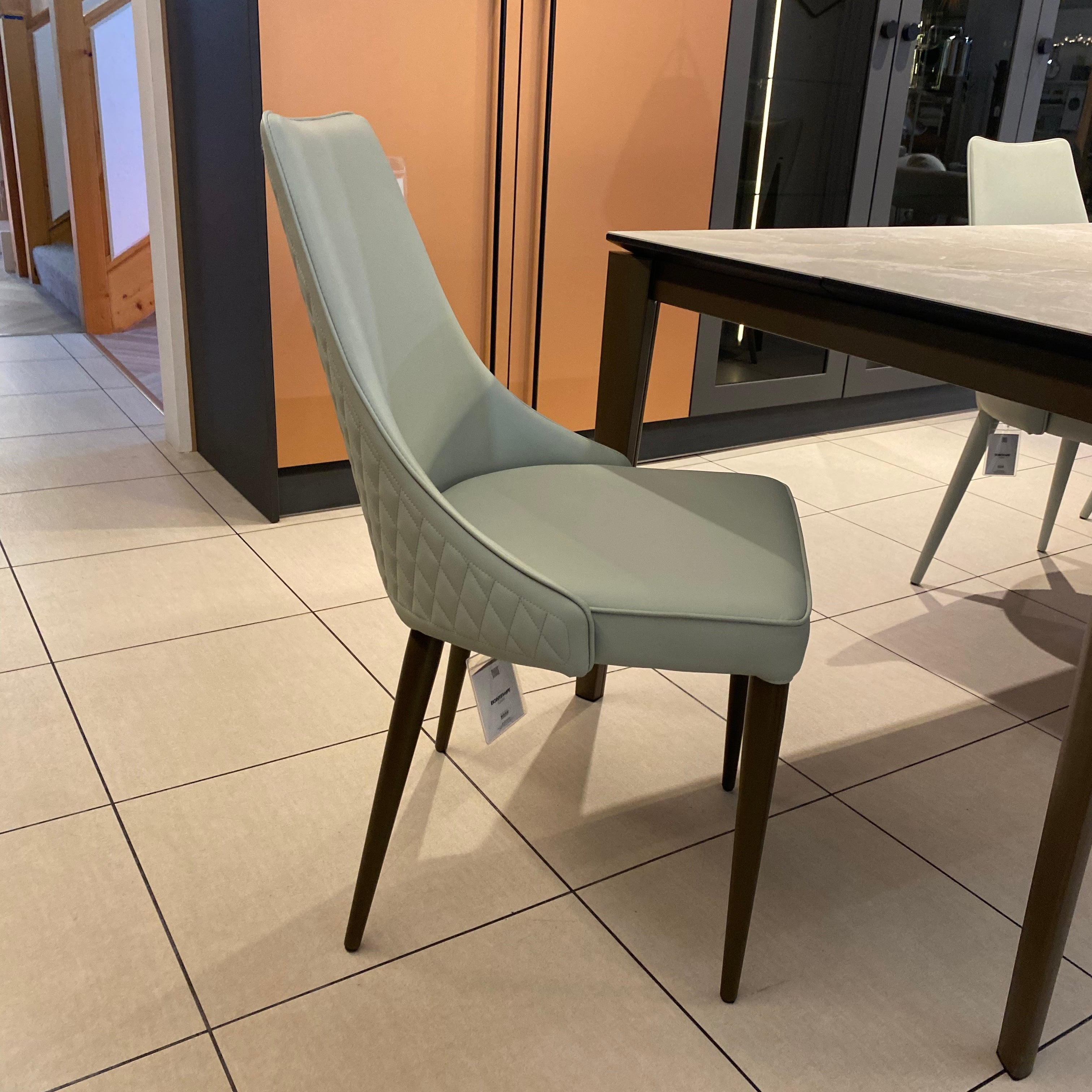 Light green chair on a tiled floor with a staircase in the background