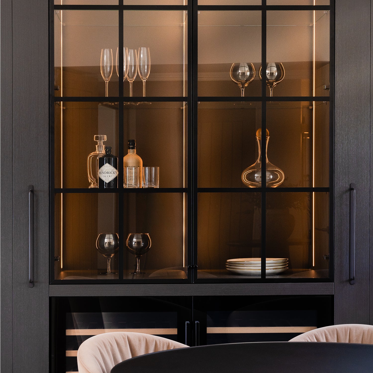 Luxury home bar cabinet with black-framed glass doors, integrated lighting, glassware display, crystal decanter – modern dark wood bar design for sophisticated dining interiors