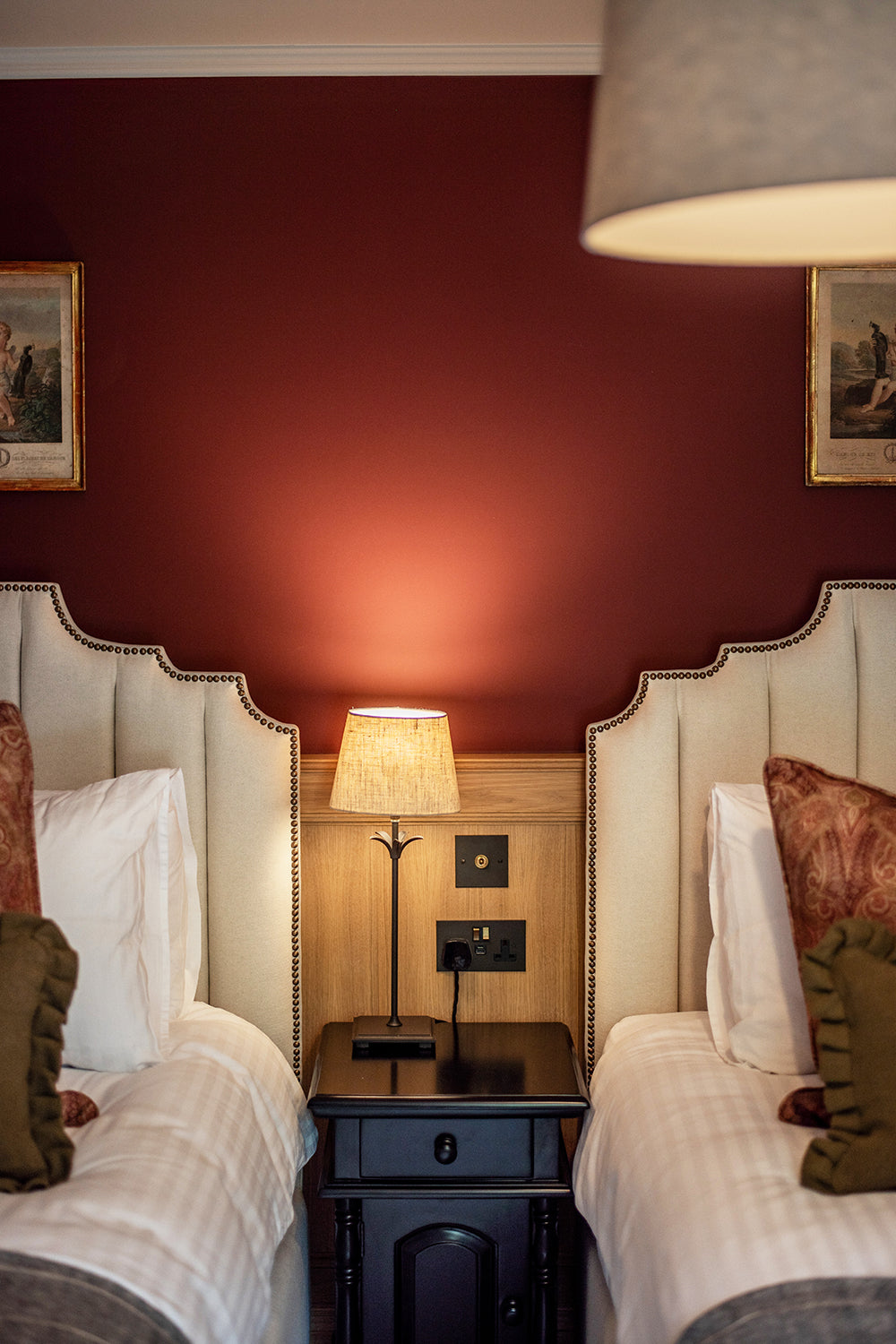 Vintage carved wooden armchair with champagne velvet upholstery, set against oak wall panelling and deep burgundy painted walls at Mariners, St Ives – a timeless blend of heritage and warmth.