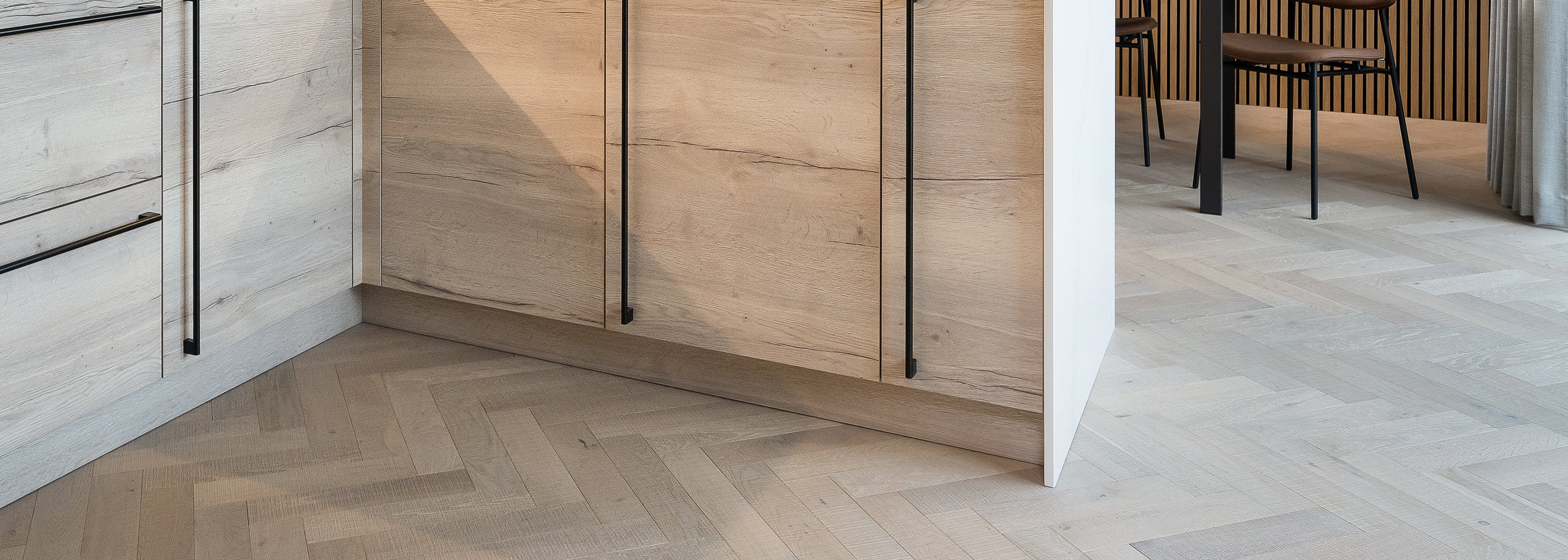Modern wood flooring in a contemporary kitchen setting, featuring wood-effect and stone-look finishes with seamless transitions – durable and stylish option for modern interiors.