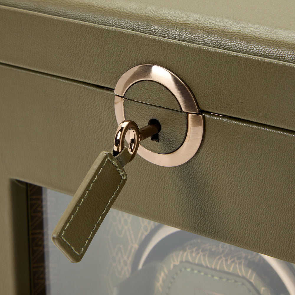 Close-up of a green watch box with a gold handle and keychain.