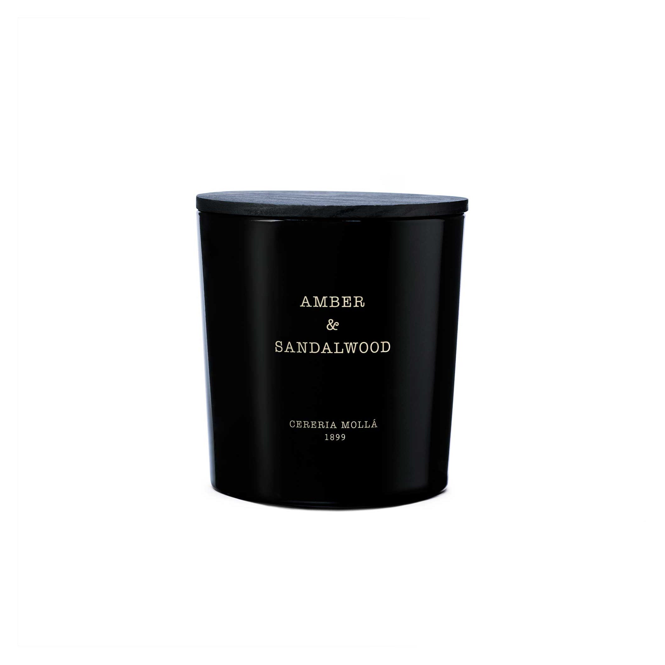 A black cylindrical candle jar with a matching black lid, featuring  text that reads 'AMBER & SANDALWOOD' and 'CERERIA MOLLA 1899' on a clean white background.