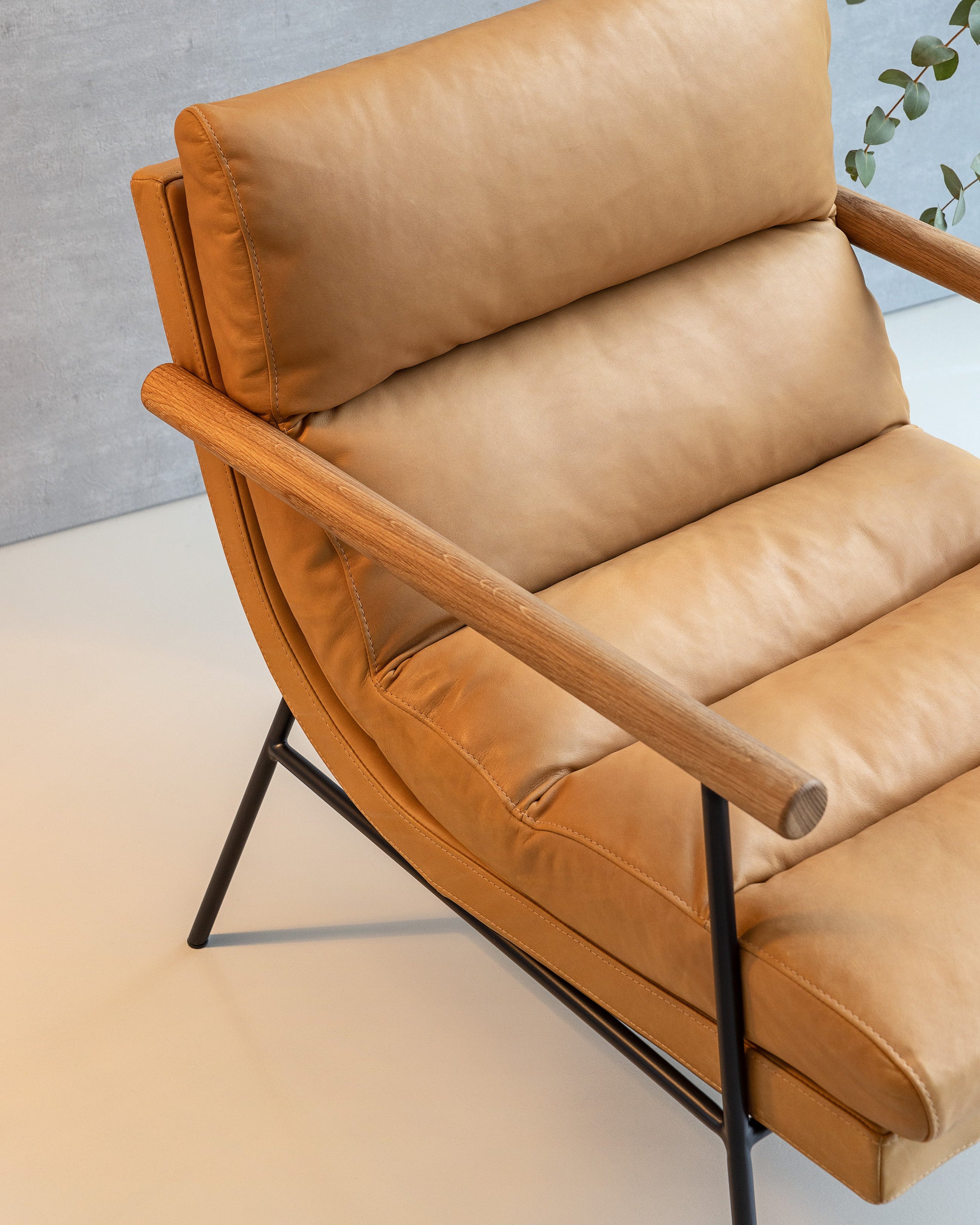 Brown leather armchair with wooden armrests on a light gray background
