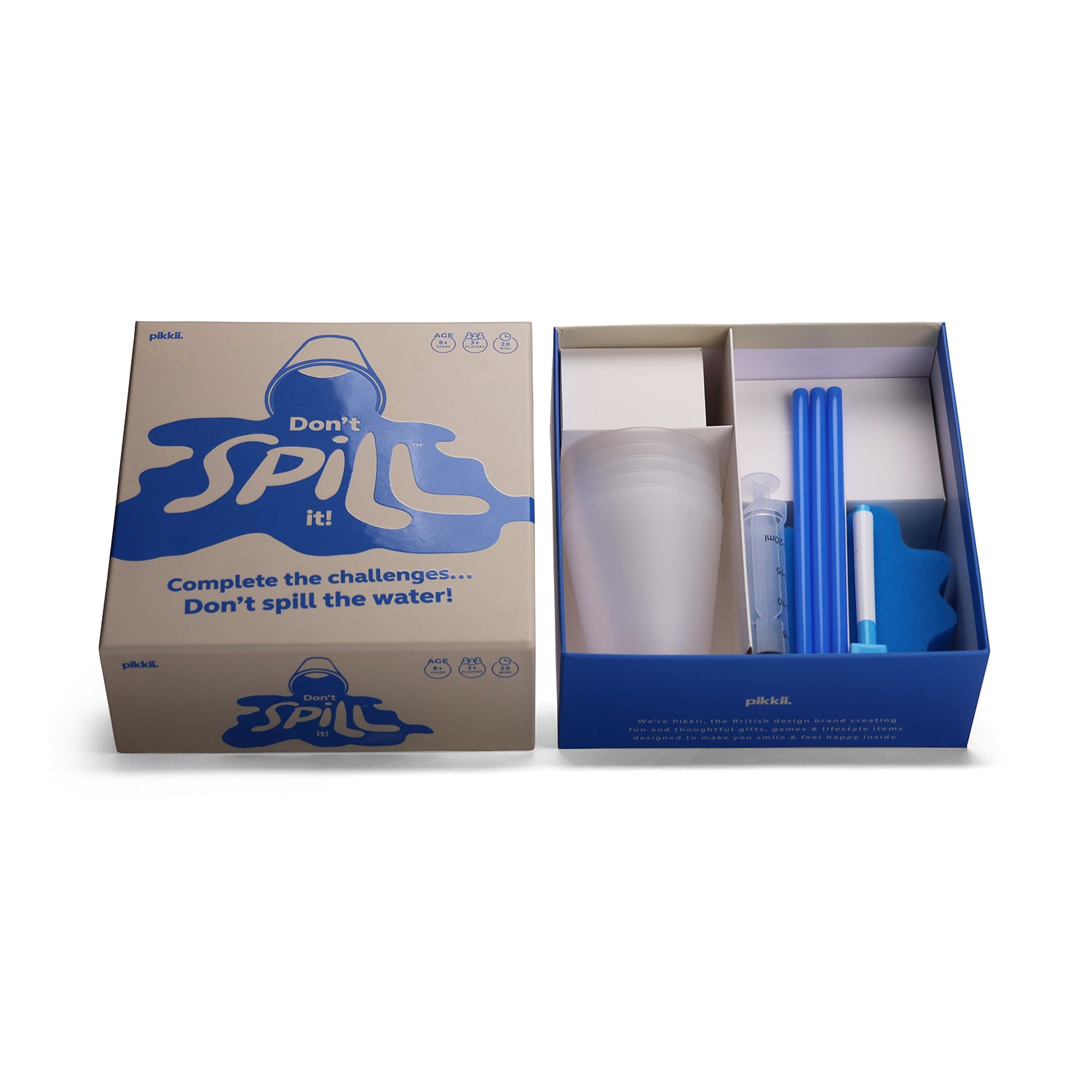DONT SPILL IT GAME shown with its outer box on the left and the opened inner tray on the right, containing a clear plastic cup, blue straws, a small bottle, and a blue insert, all on a white background.