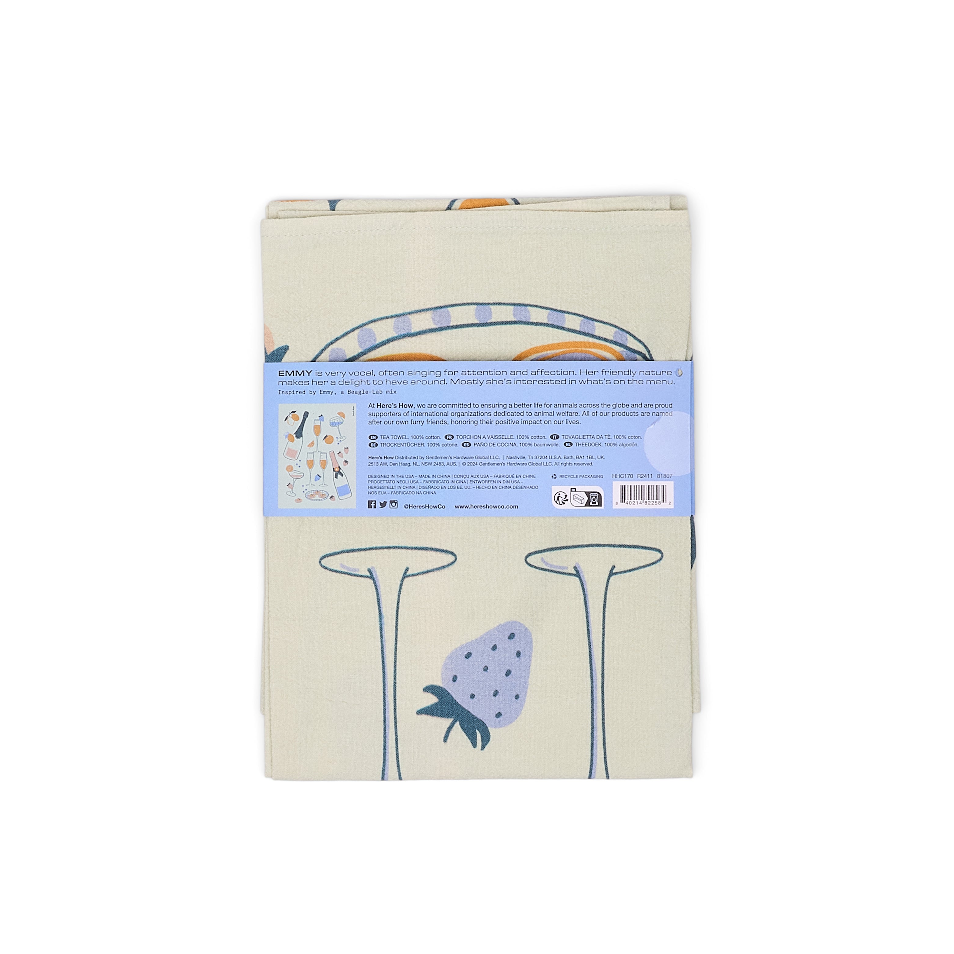 A folded tea towel with a light beige base, featuring a blue strawberry. A light blue paper label is wrapped around the middle with product details.