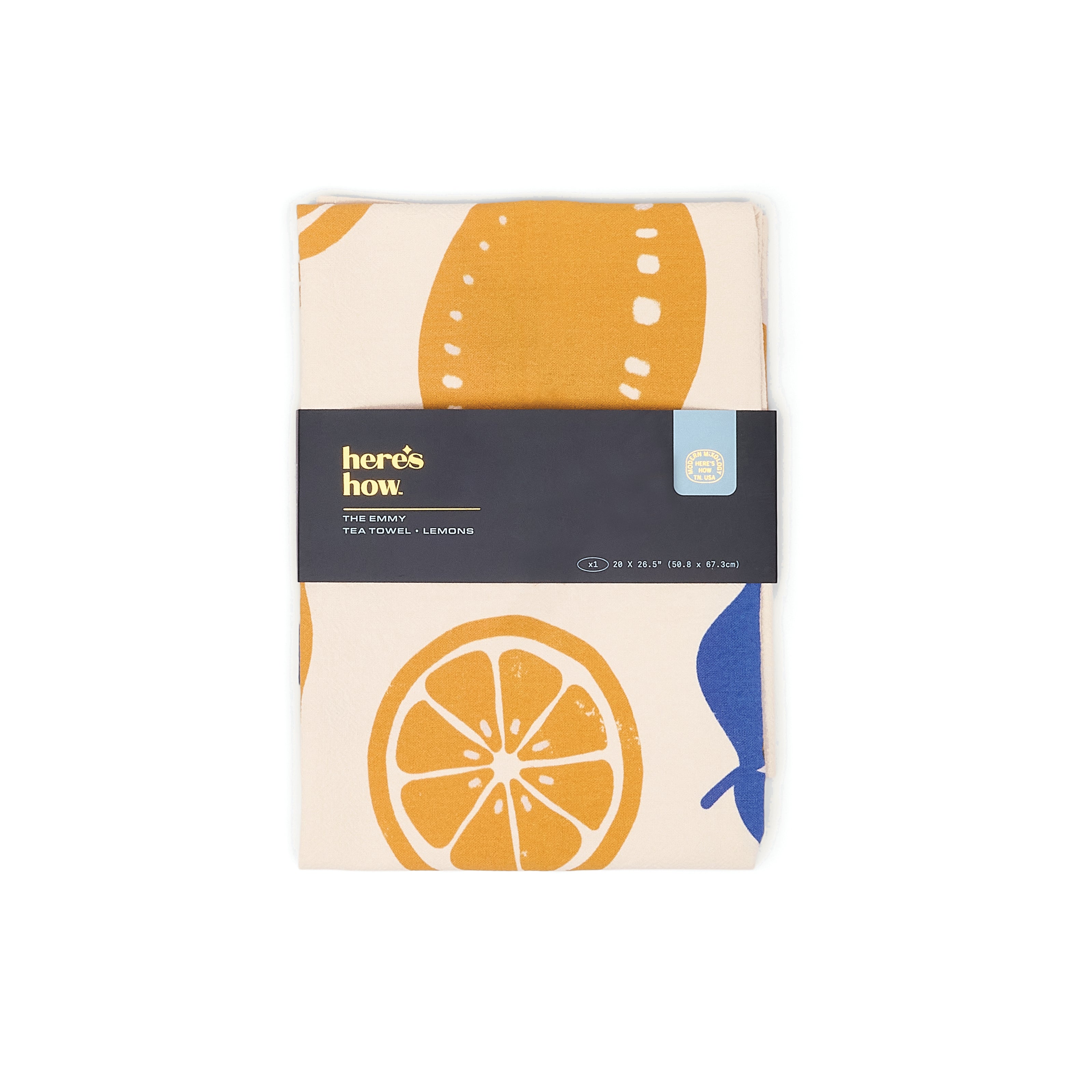 A folded cotton tea towel from here's how. featuring a lemon pattern on a cream background.