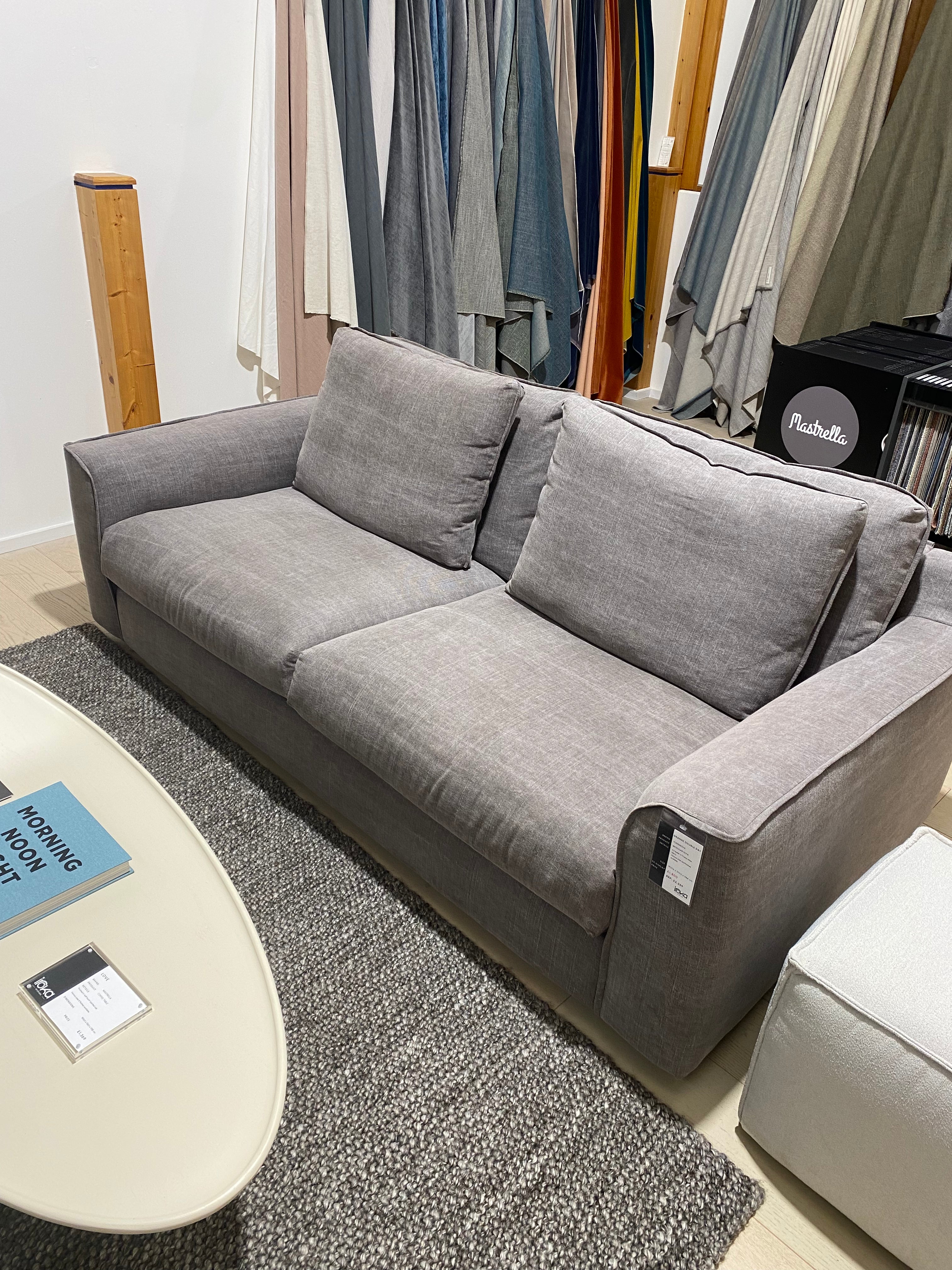 Gray sectional sofa in a showroom setting with color swatches in the background