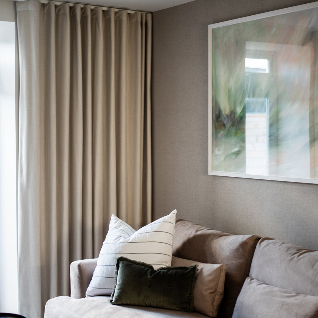 Living room with a beige sofa, striped cushions, and a abstract painting on the wall.