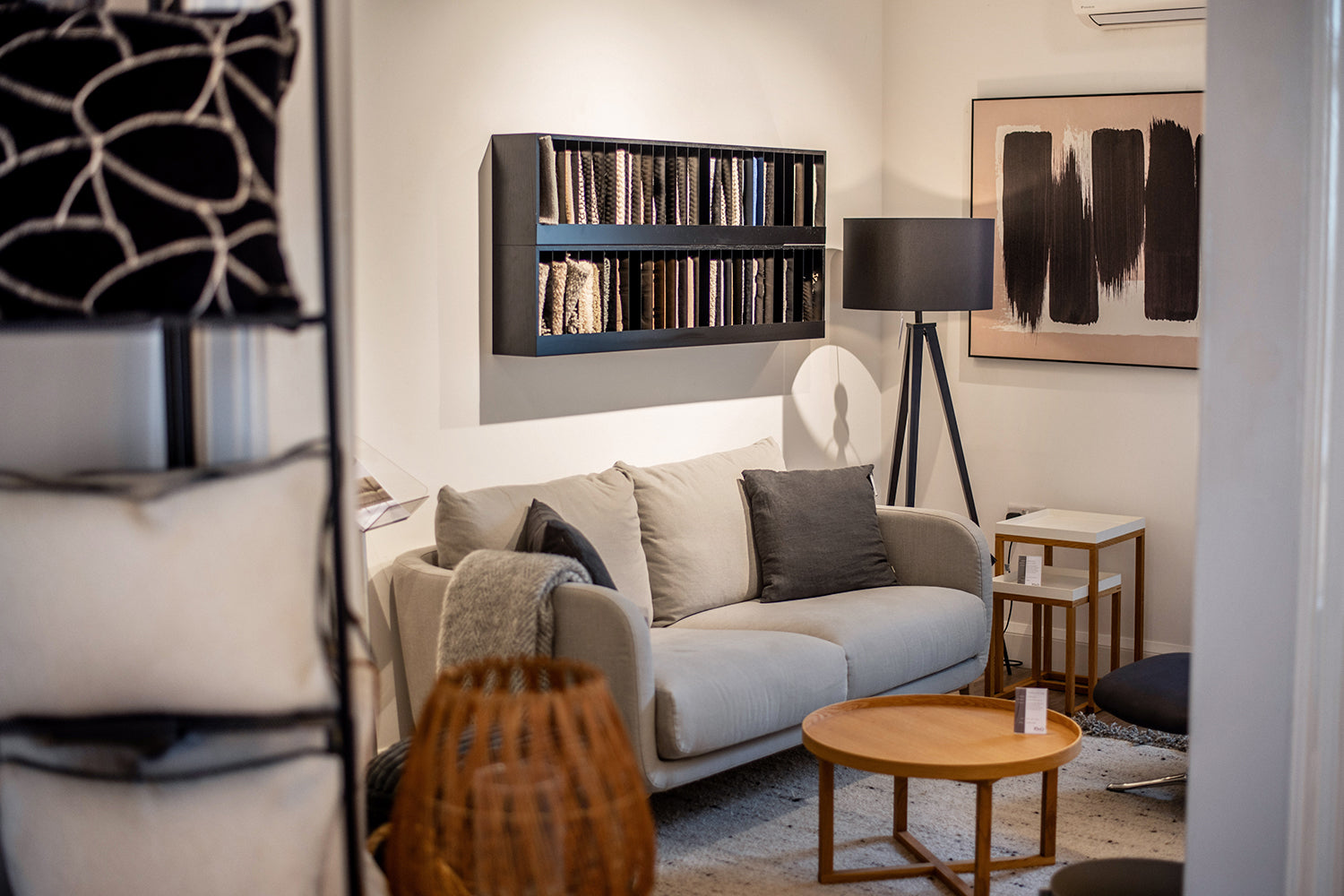Small living room set with grey 2 seater sofa. Black accents throughout the room and abstract neutral artwork to compliment.