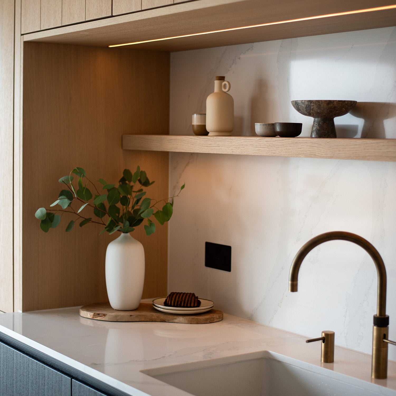 Kitchen Counter close up, minimalistic design with wooden shelf and smart lighting features. Modern tap and sink finishes with marble counter.