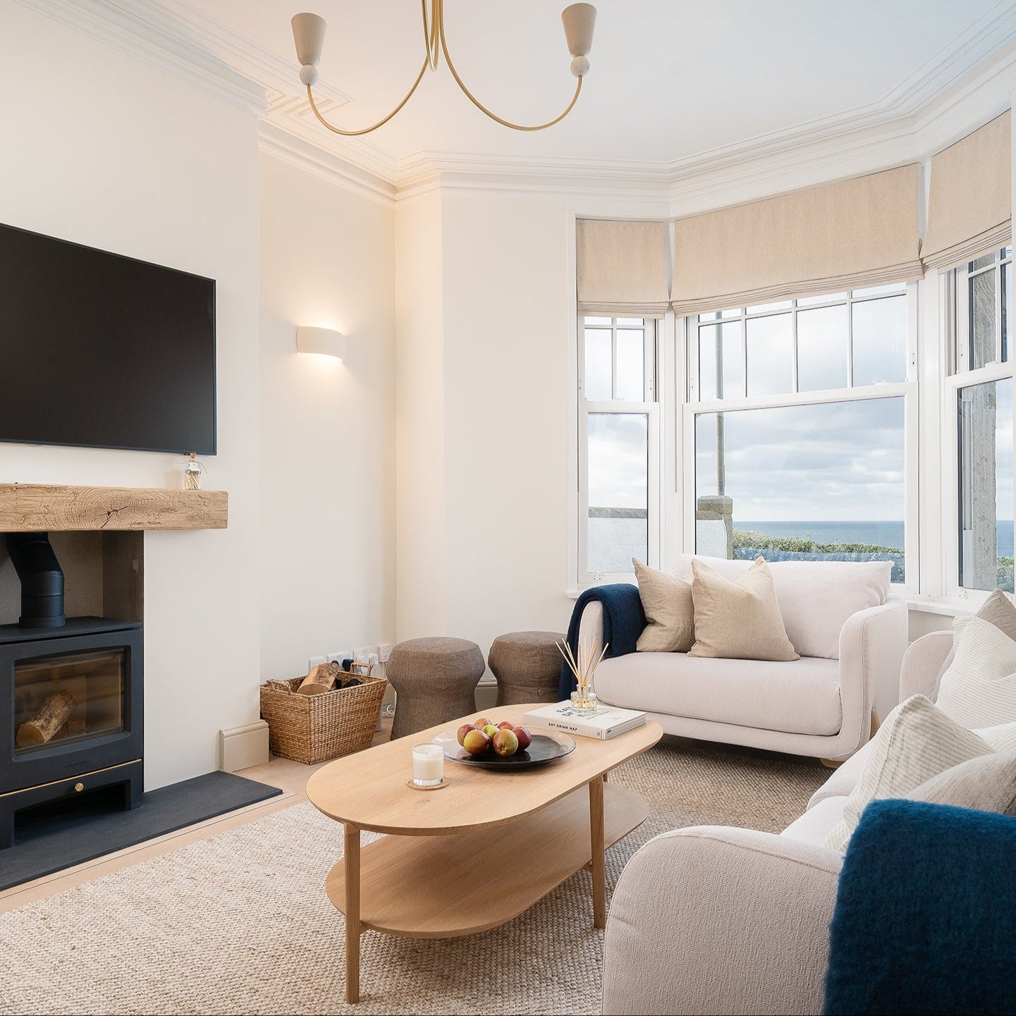 Modern living room with white sofas, a wooden coffee table, and large windows.